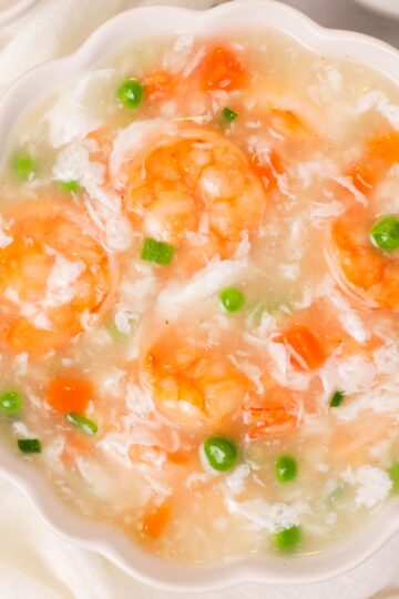 Shrimp with lobster sauce in a white scalloped bowl.