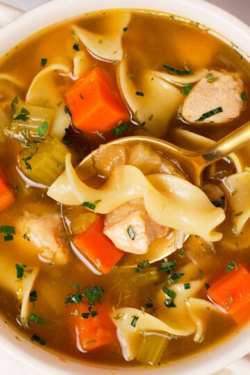Holding a spoonful of chicken noodle soup.