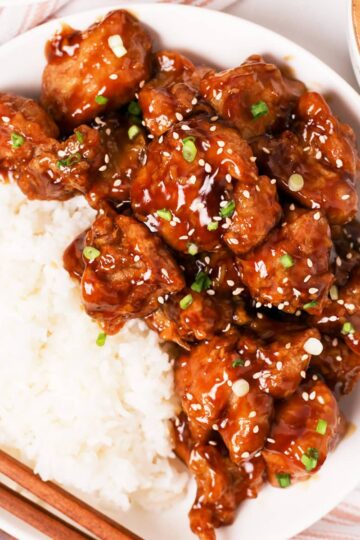 A plate of bourbon chicken with white rice.