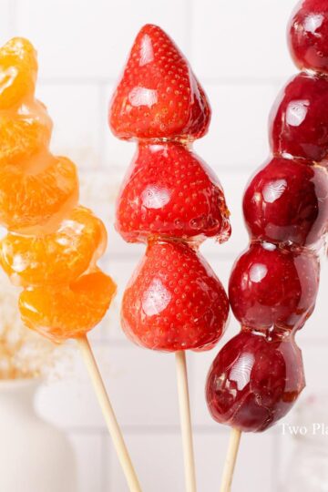 A skewer of orange, strawberry, and grape tanghulu.