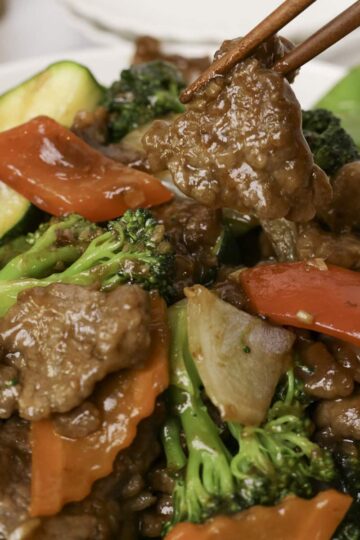 Picking up a sliced of stir fry beef with brown sauce.