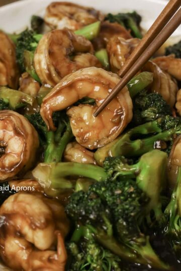 Picking up a shrimp from a plate of shrimp and broccoli.