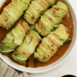 Chicken cabbage rolls served on a plate with sauce and garnish.