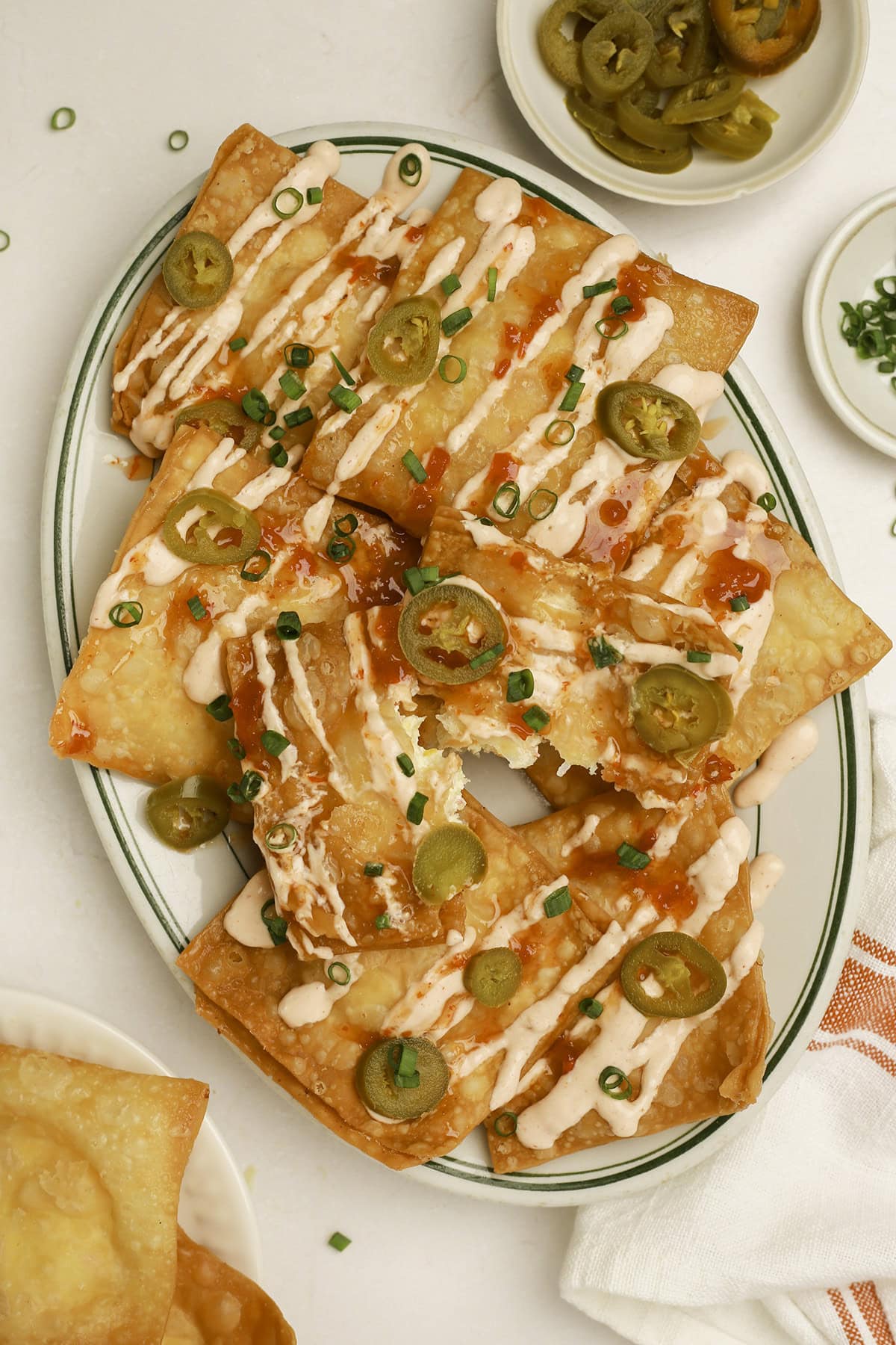 A plate of crab rangoon nachos with one piece torn in half.