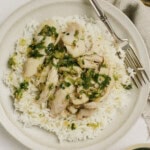 Steamed chicken with ginger scallion sauce served over a plate of rice.
