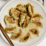 A plate of pork gyoza with crispy skirt.