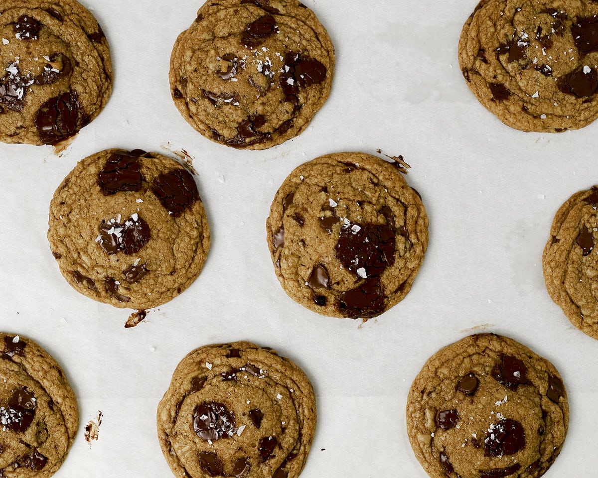 Baked brown butter chocolate chip cookies on parchment paper.