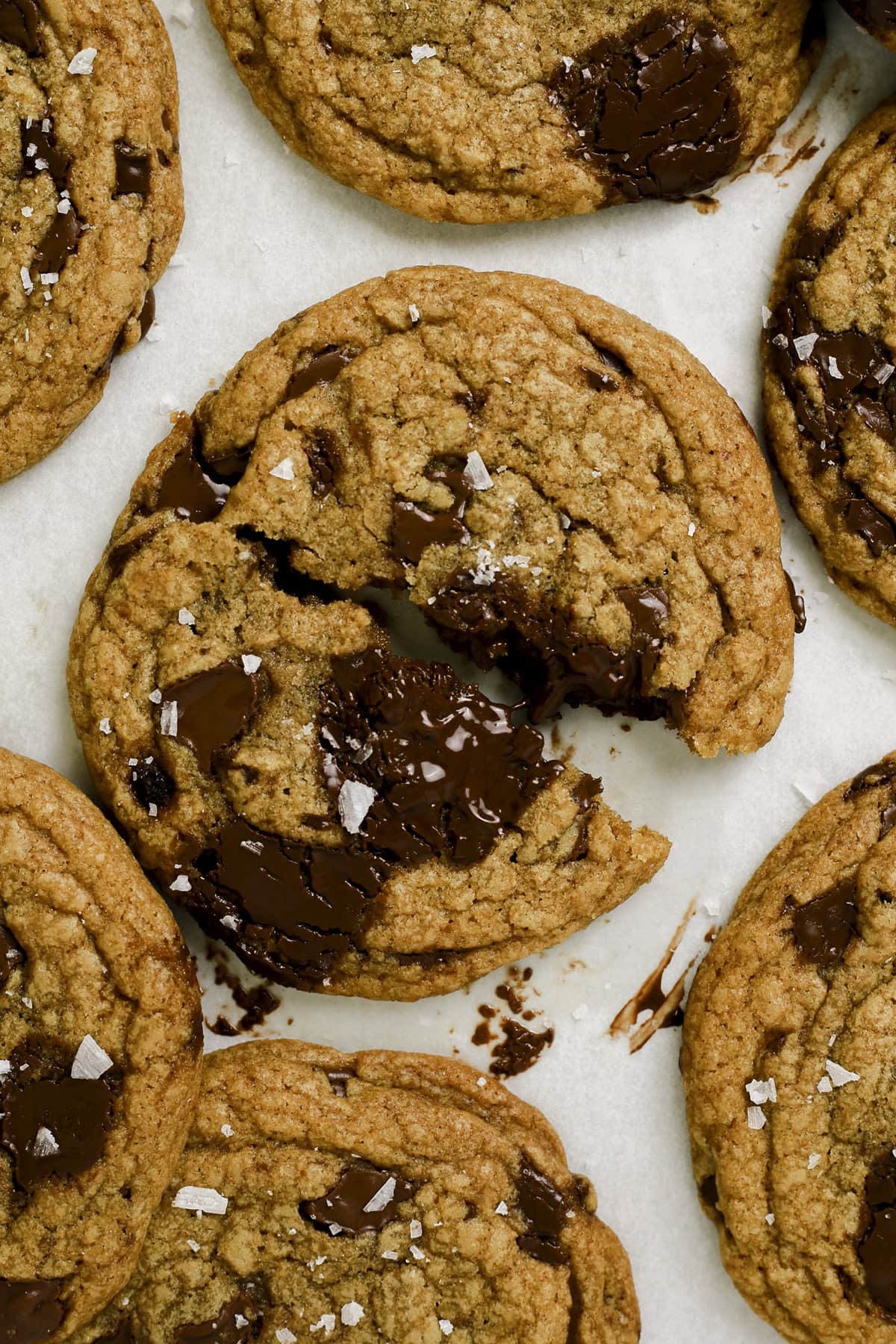 A tray of brown butter chocolate chip cookies with one split in half.