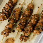 Teriyaki chicken skewers with green onion and togarashi.