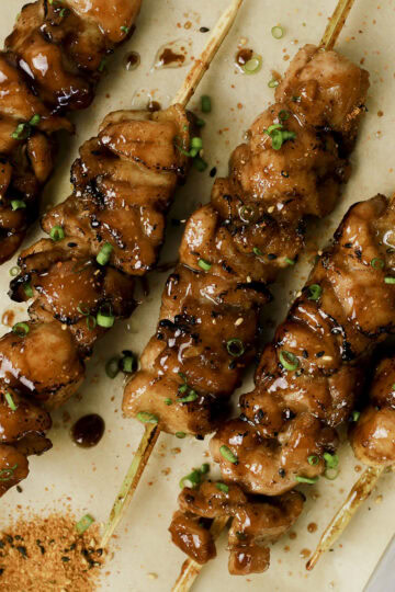 Teriyaki chicken skewers with green onion and togarashi.